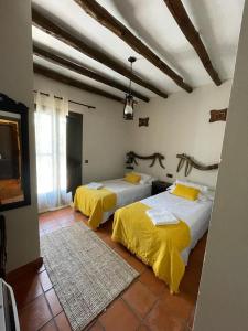 a bedroom with two beds with yellow sheets at Hotel La Hoya del Tajo in Ronda