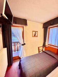 a bedroom with a bed and a large window at HOTEL LA NIGRITELLA in Bardonecchia