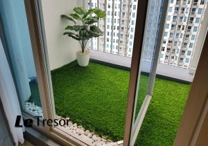 a balcony with green grass and a plant at Le Tresor Benson Apartment at Supermal Pakuwon in Surabaya