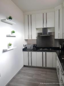 una cocina con armarios blancos y encimeras negras en Departamento Glorieta en Mazamitla