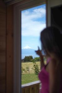 a woman looking at a mountain through a window at Ave Lodge Frutillar in Frutillar