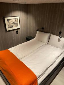 a large white bed with an orange blanket on it at Ny leilighet i Henningsvær! in Henningsvær