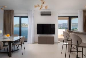 a living room with a television and a table and chairs at Villa Palm Bay 2, heated pool - 10 m from the sea in Ražanj