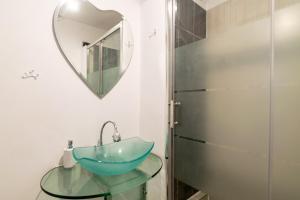 baño con lavabo de cristal y espejo en Apartament Brazda - Rendez Vous, en Craiova