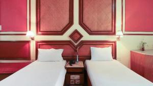 2 Betten in einem Zimmer mit roten Wänden in der Unterkunft Bengal Chambers in Kalkutta