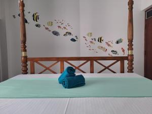 a blue stuffed animal sitting on a bed at The Pearl Palace in Weligama
