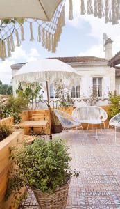 un patio con mesas, sillas y una sombrilla en Maison Charmeilles - Gîte touristique - Coliving en Fronsac