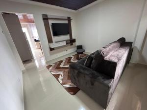 a living room with a couch and a television at Aconchego, no melhor lugar de Foz! in Foz do Iguaçu