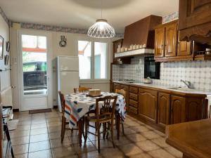 eine Küche mit einem Tisch und Stühlen sowie einem Kühlschrank in der Unterkunft Les clés de Jonzacconciergerie, Villa les oiseaux in Jonzac