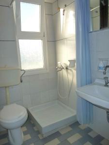 a white bathroom with a toilet and a sink at Paris Beach Hotel in Ireon