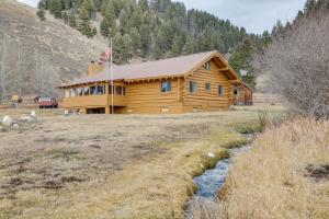 a log cabin with a stream in front of it at Yellowstone Cabin Getaway Near National Park in Cliff Lake