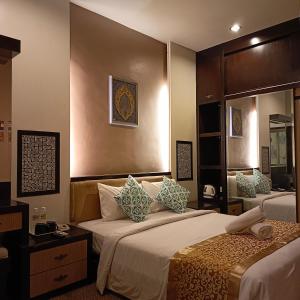 a hotel room with two beds and a mirror at Hotel Zara in Sungai Petani