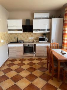 a kitchen with white cabinets and a table with chairs at Vadviraghaz in Palkonya