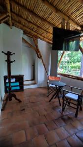 a room with a table and a bench and a television at Cabañas Coloniales con Entorno Natural en Barichara in Barichara