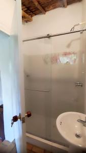 una ducha con una puerta de cristal junto a un lavabo en Cabañas Coloniales con Entorno Natural en Barichara en Barichara