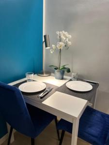 een tafel met twee witte borden en een blauwe stoel bij Casa di Susi in Milaan