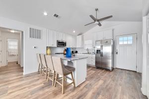 a kitchen with white cabinets and a bar with chairs at Flip Flops & Sun in Gulf Shores