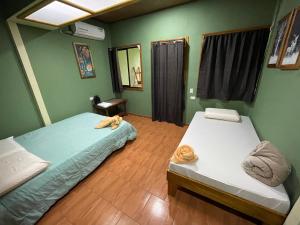 two beds in a room with green walls and wooden floors at Ceiba lodge in Drake