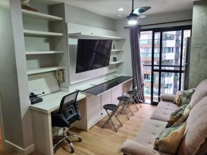 a living room with a couch and a desk with a tv at Flat Hotel Mercure - 4 Estrelas Moema SP in Sao Paulo