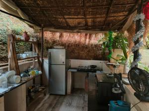 a small kitchen with a refrigerator and a table at Rooms in Greek Jungle Villa, Thalassa Road in Siolim