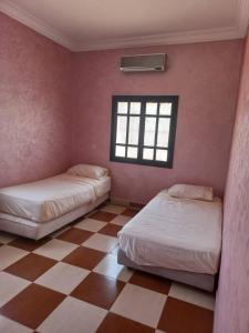 2 Betten in einem Zimmer mit kariertem Boden in der Unterkunft Villa Générosité in Marrakesch
