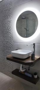 La salle de bains est pourvue d'un lavabo blanc et d'un miroir. dans l'établissement Superior Seaview Apartment, à Antirrio