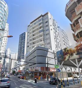 un edificio alto en una calle de la ciudad con coches en Apartamento central próximo da praia e atlântico shopping, en Balneário Camboriú