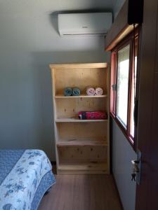 a bedroom with a bed and a shelf with clothes at Nuestro sueño 2 in Colonia del Sacramento
