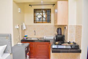 a small kitchen with a sink and a stove at Evans' Cosy Studio Home in Mombasa