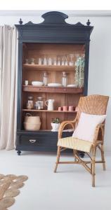 a chair in front of a cabinet with dishes at Maison Charmeilles - Le studio Canon de Fronsac in Fronsac