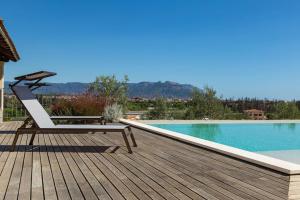 a wooden deck with a chair next to a swimming pool at Dimore Santa Justa in Tortolì
