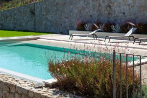 a swimming pool with three chairs and flowers in a yard at Dimore Santa Justa in Tortolì