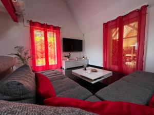 a living room with red curtains and a couch at Villa avec piscine à 10 min du circuit des 24h du Mans in Spay