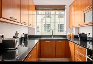 a kitchen with wooden cabinets and a sink and a window at Luxury 4 Bed Knights Bridge in London