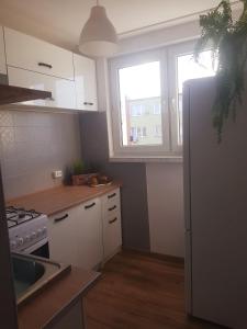 a kitchen with white cabinets and a white refrigerator at Irra Apartment in Gdańsk