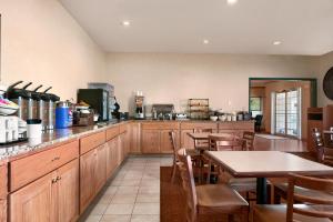 a kitchen with wooden cabinets and tables and chairs at Country Inn & Suites by Radisson, Clinton, IA in Clinton