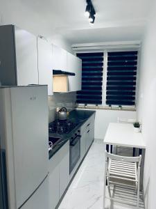 kuchnia z białymi szafkami, kuchenką i stołem w obiekcie ClickTheFlat Karmelicka Apart Rooms w Warszawie