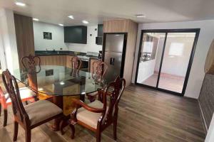a kitchen with a glass table and chairs and a refrigerator at Cabaña Alpina in Creel