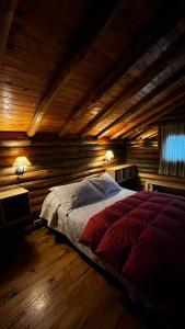 Cama grande en habitación con paredes de madera en Cabaña Suiza en Cacheuta