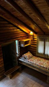 a bedroom in a log cabin with a bed and a tv at Cabaña Suiza in Cacheuta
