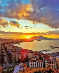- une vue sur une ville avec le coucher du soleil en arrière-plan dans l'établissement Naples Luxury Suites B&B, à Naples
