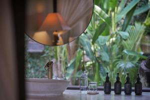 a counter with bottles and a sink and a mirror at The Damai in Lovina
