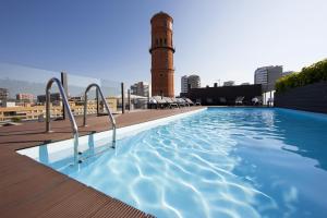 a swimming pool on the roof of a building with a clock tower at Attica 21 Barcelona Mar in Barcelona