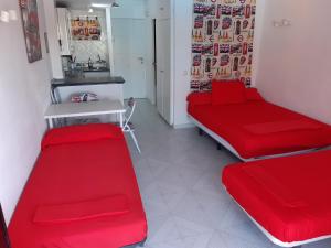 Habitación con 2 camas rojas y cocina. en Minerva Apartments Sea View en Benalmádena