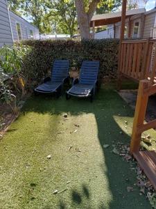 two blue chairs sitting on the grass in a yard at camping 4 étoiles SIBLU Les sables du midi in Valras-Plage