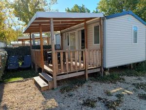 a small cabin with a deck with a table at camping 4 étoiles SIBLU Les sables du midi in Valras-Plage
