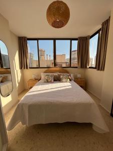 a bedroom with a large white bed with windows at Apartamento las OLAS playa de levante in Benidorm