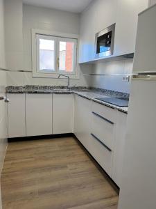 a kitchen with white cabinets and a sink and a window at Apartamento las OLAS playa de levante in Benidorm