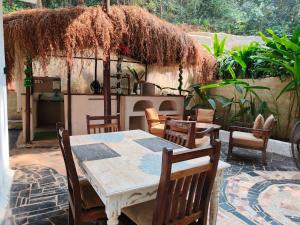 een tafel en stoelen en een keuken in de tuin bij Rooms in Greek Jungle Villa, Thalassa Road in Siolim