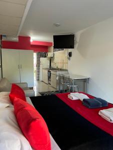 a room with red pillows on a bed with a kitchen at Apart & Hotel Neptuno in Valeria del Mar